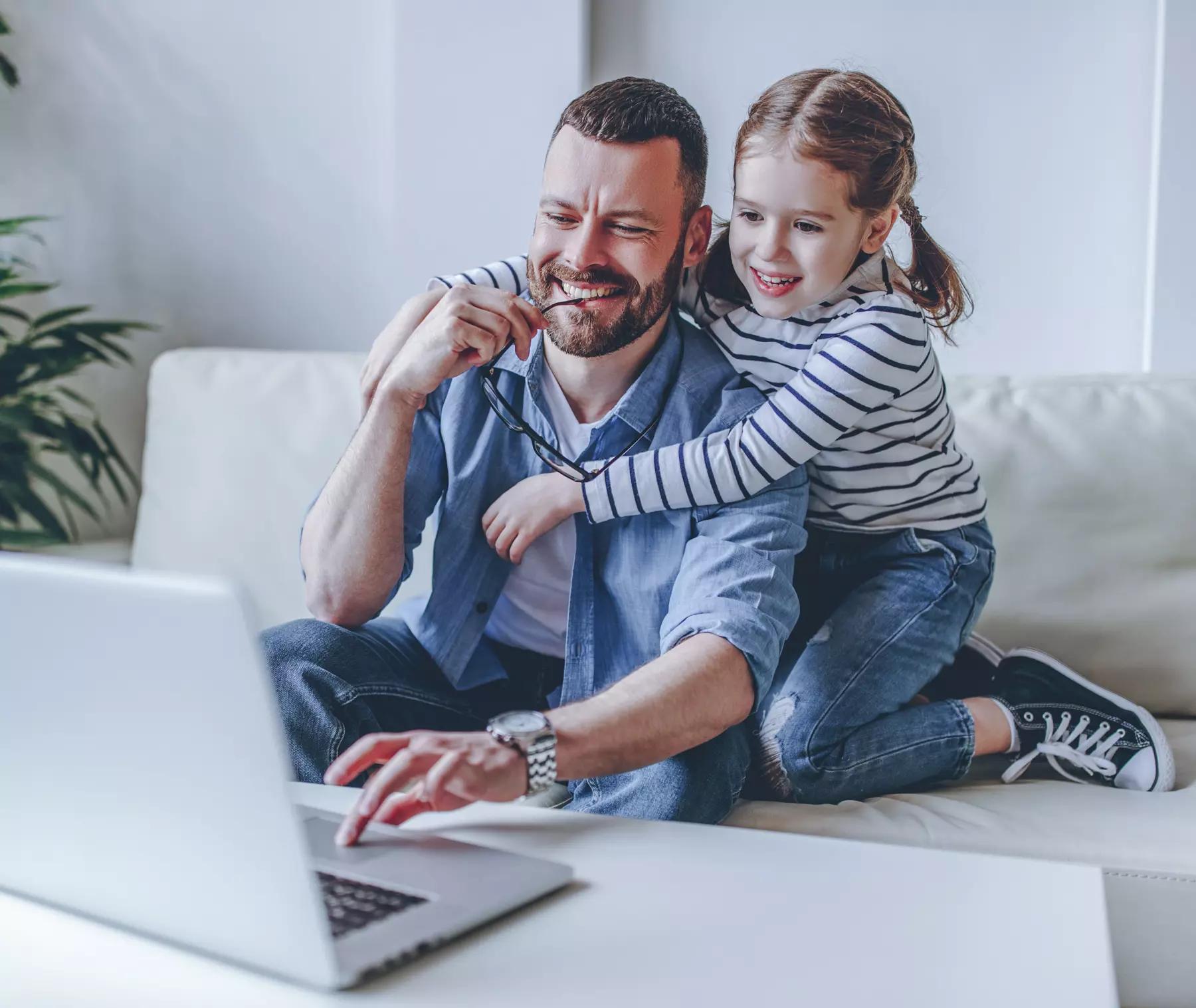 father working at computer and his child daughter at home