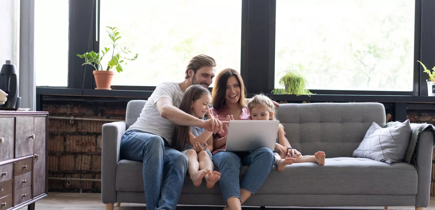 parents sitting on the couch with their children smiling and looking at the computer