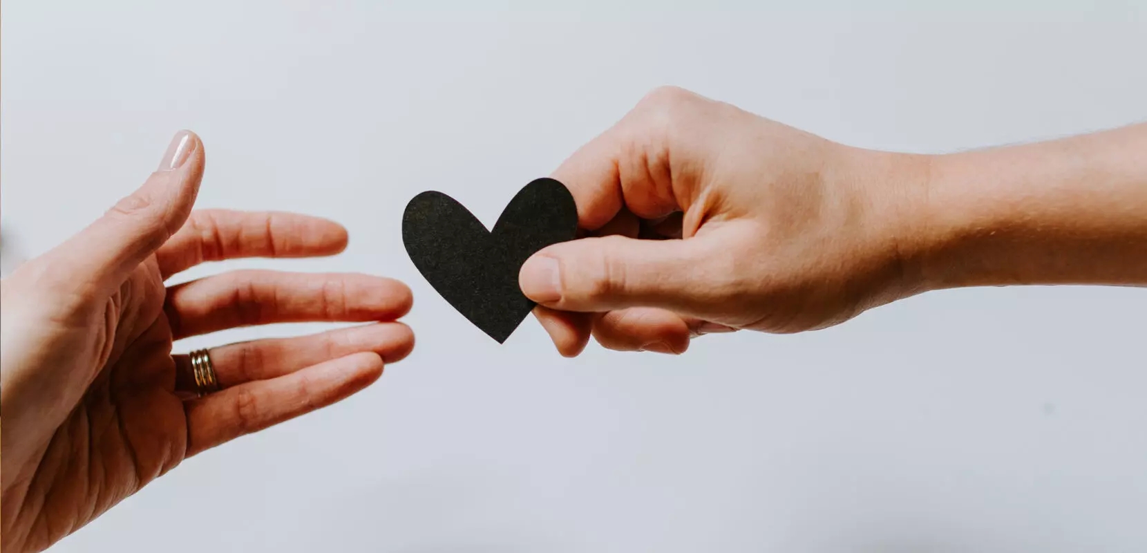 a hand passing a paper heart to another hand