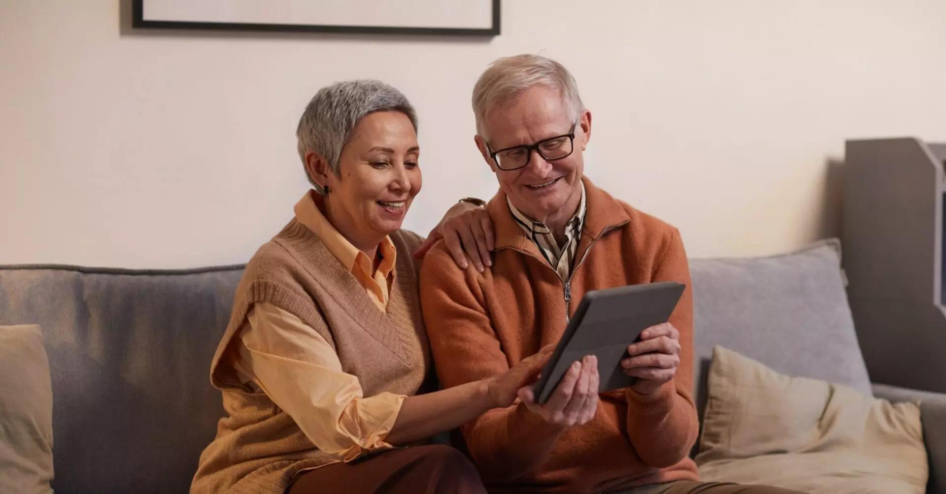 a husband and wife sit on the couch with their ipad to go over what they need to know about charitable giving and taxes for 2023